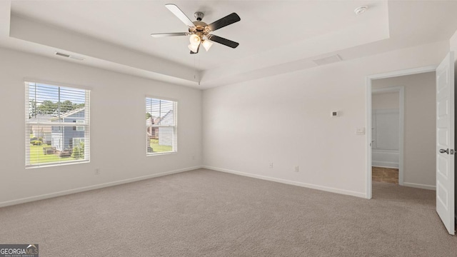 carpeted spare room featuring a raised ceiling and ceiling fan