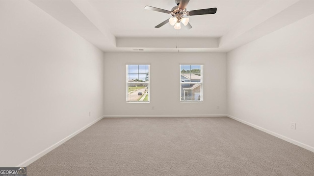 carpeted empty room featuring a tray ceiling and ceiling fan