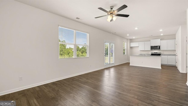 unfurnished living room featuring dark wood-type flooring and ceiling fan