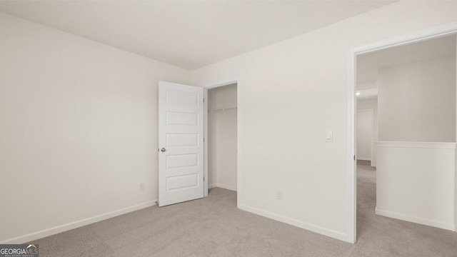 unfurnished bedroom with light colored carpet and a closet