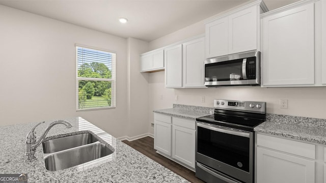 kitchen with dark wood-type flooring, sink, white cabinetry, stainless steel appliances, and light stone countertops