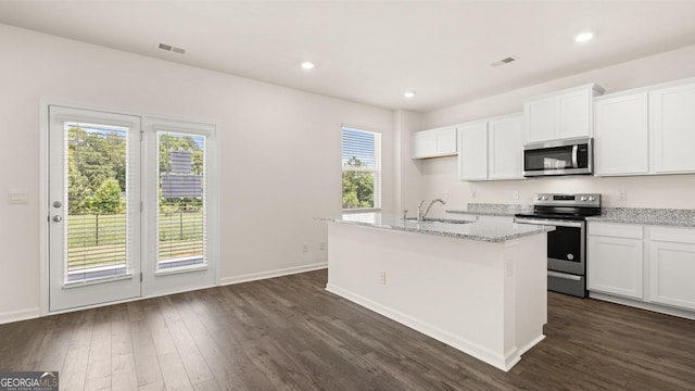 kitchen with light stone counters, dark hardwood / wood-style floors, stainless steel appliances, a kitchen island with sink, and white cabinets