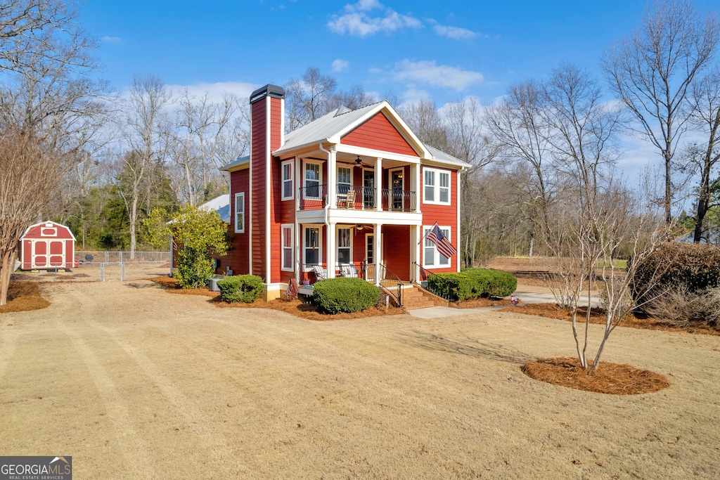 view of front of property with a storage unit, a balcony, and a porch