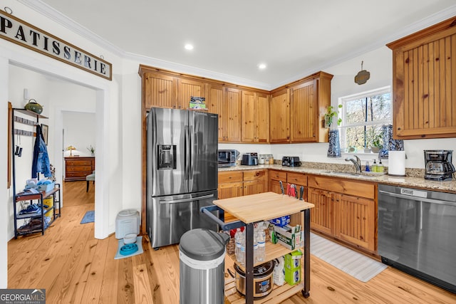 kitchen with sink, light stone counters, light hardwood / wood-style flooring, ornamental molding, and stainless steel appliances