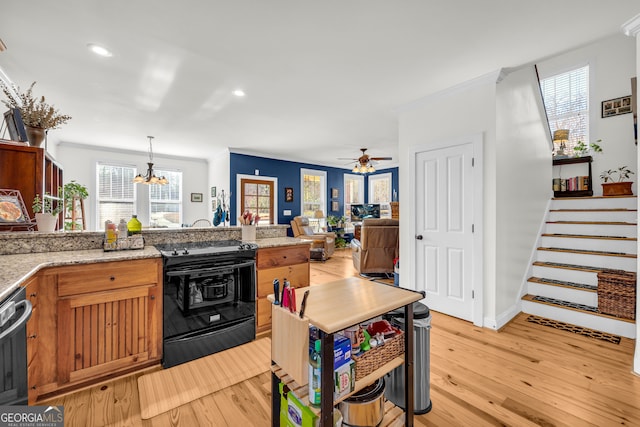 kitchen with black range, decorative light fixtures, light stone countertops, and light hardwood / wood-style flooring