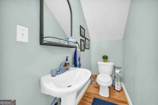 bathroom featuring vaulted ceiling, sink, hardwood / wood-style floors, and toilet