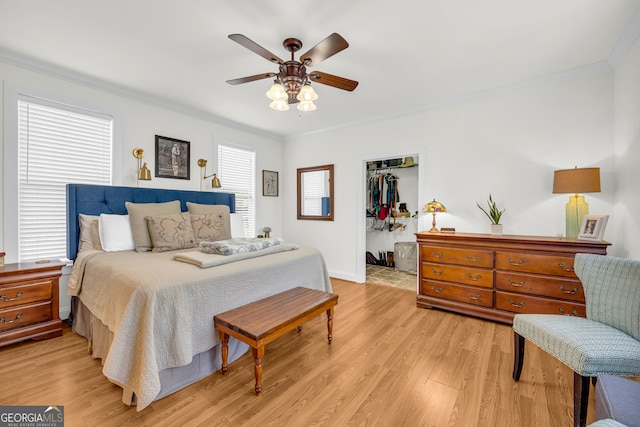 bedroom featuring ornamental molding, a walk in closet, light hardwood / wood-style floors, and a closet