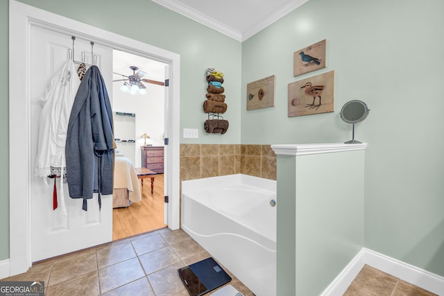 bathroom featuring tile patterned flooring, crown molding, ceiling fan, and a tub to relax in