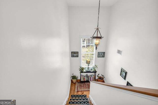 stairway featuring wood-type flooring and a chandelier