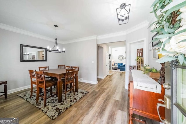 dining room with wood-type flooring, crown molding, and an inviting chandelier