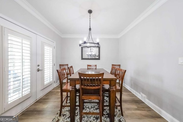 dining room with crown molding, dark hardwood / wood-style floors, french doors, and a notable chandelier