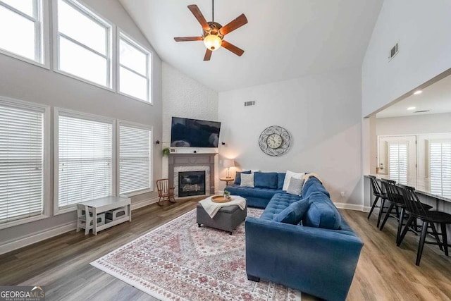 living room with ceiling fan, high vaulted ceiling, a fireplace, and hardwood / wood-style floors