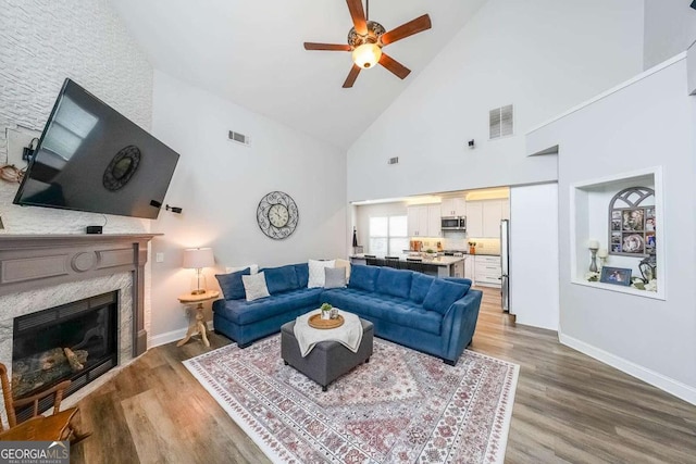 living room featuring hardwood / wood-style flooring, ceiling fan, lofted ceiling, and a fireplace