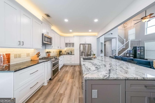 kitchen with sink, dark stone counters, white cabinets, and appliances with stainless steel finishes