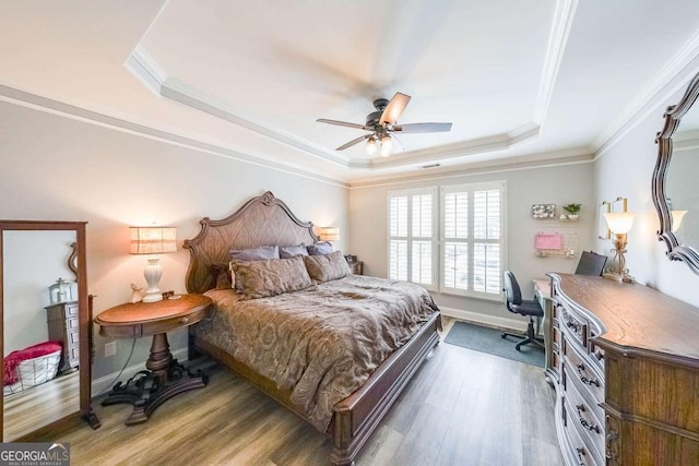 bedroom with dark wood-type flooring, ceiling fan, ornamental molding, and a raised ceiling