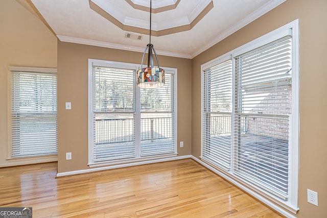 unfurnished dining area featuring ornamental molding, hardwood / wood-style floors, and a tray ceiling