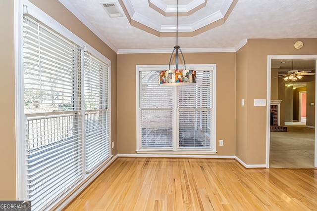 unfurnished dining area featuring ceiling fan, ornamental molding, a fireplace, and hardwood / wood-style floors