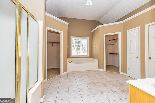 bathroom with lofted ceiling, tile patterned floors, a textured ceiling, and vanity