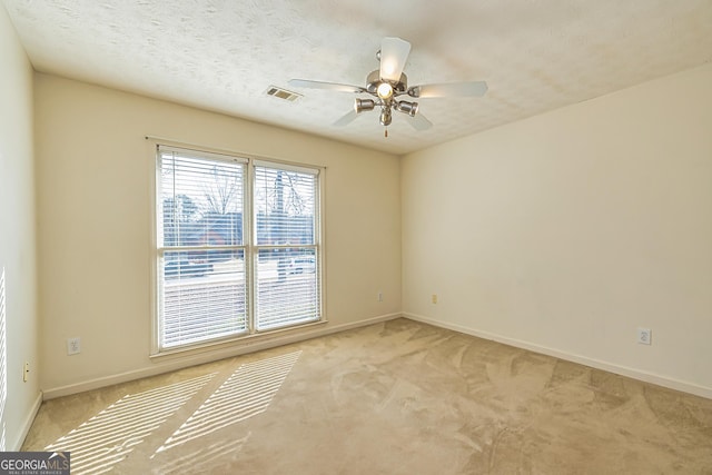 carpeted spare room featuring ceiling fan and a textured ceiling