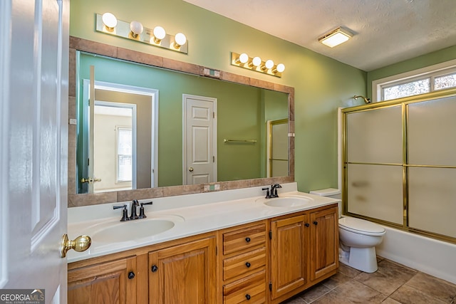 full bathroom featuring tile patterned floors, toilet, a textured ceiling, vanity, and enclosed tub / shower combo