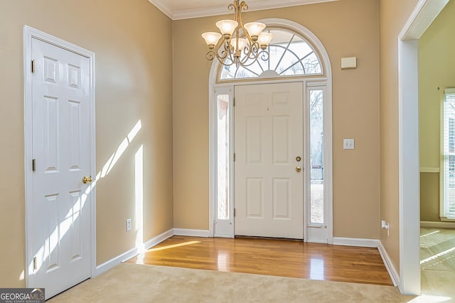 foyer entrance with ornamental molding, an inviting chandelier, and light hardwood / wood-style flooring