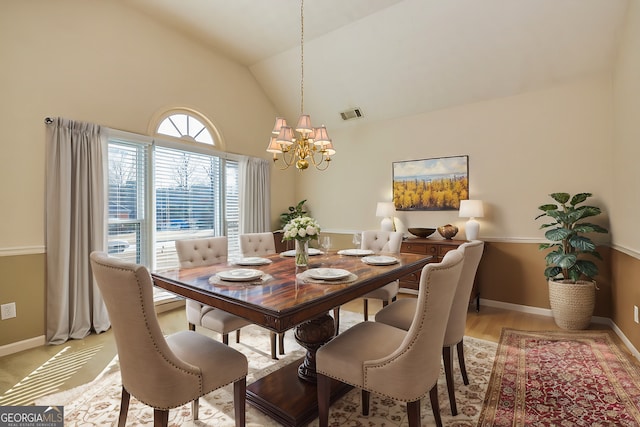 dining space with a notable chandelier, high vaulted ceiling, and light hardwood / wood-style flooring