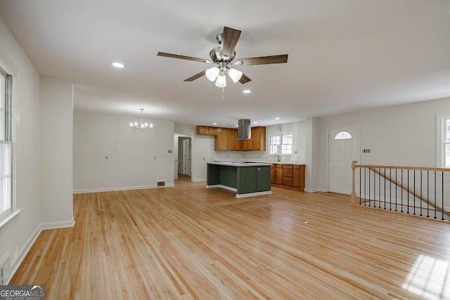 kitchen with sink, hanging light fixtures, a kitchen island, island exhaust hood, and light wood-type flooring