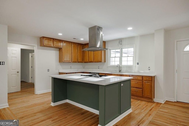 kitchen with island exhaust hood, a center island, sink, and light hardwood / wood-style floors