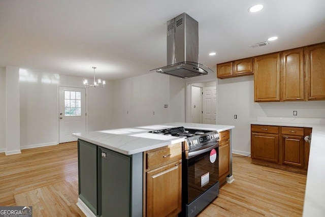 kitchen featuring island exhaust hood, stainless steel gas range, light hardwood / wood-style floors, and a kitchen island