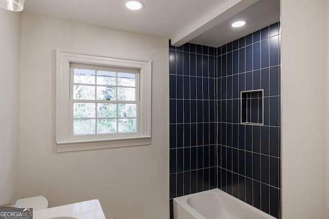 bathroom with toilet and tiled shower / bath