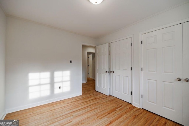 unfurnished bedroom featuring crown molding and light wood-type flooring