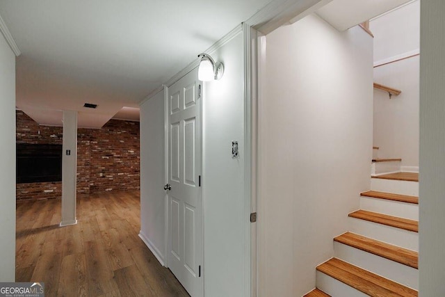 hall featuring brick wall and hardwood / wood-style floors