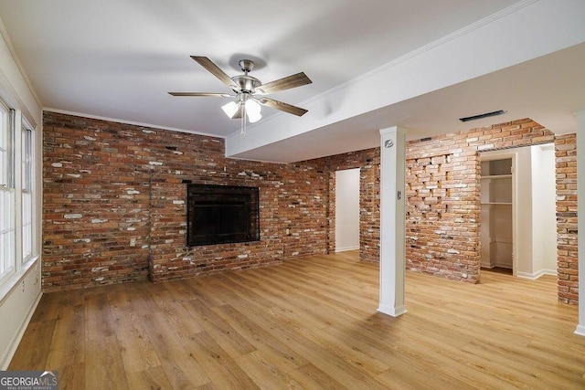 unfurnished living room featuring a brick fireplace, light hardwood / wood-style flooring, ornamental molding, and brick wall