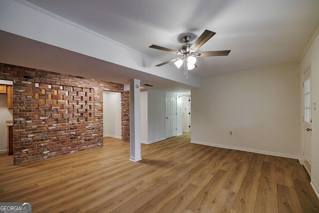 unfurnished living room with ceiling fan, ornamental molding, brick wall, and light hardwood / wood-style flooring