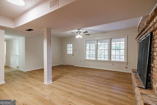 unfurnished living room featuring ceiling fan, ornamental molding, light hardwood / wood-style floors, and a brick fireplace