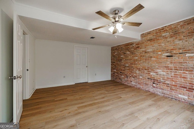 unfurnished room with ceiling fan, brick wall, ornamental molding, and light wood-type flooring