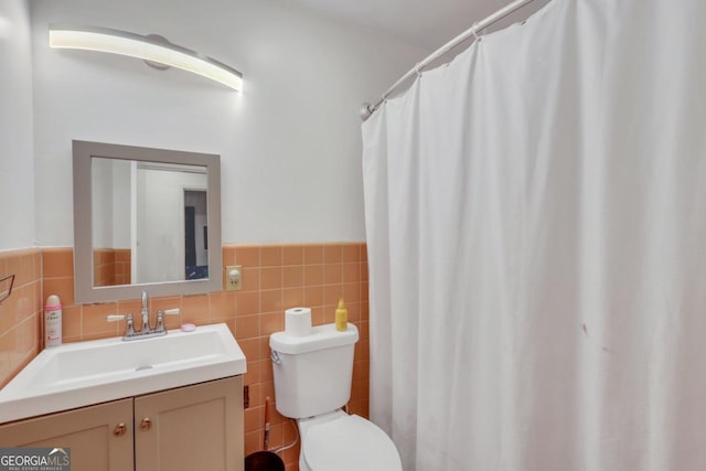 bathroom featuring vanity, toilet, and tile walls