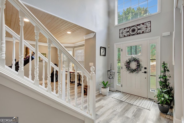 foyer with a towering ceiling, hardwood / wood-style floors, and wooden ceiling