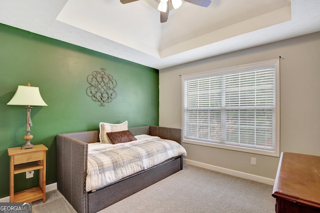 bedroom with a raised ceiling, carpet floors, and ceiling fan