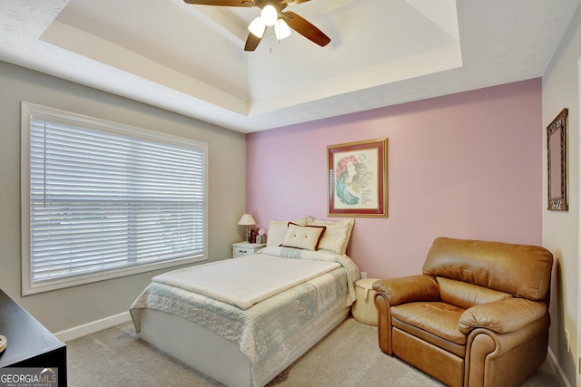 carpeted bedroom featuring ceiling fan and a raised ceiling