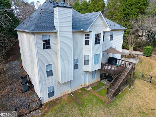 rear view of property featuring a wooden deck and a lawn