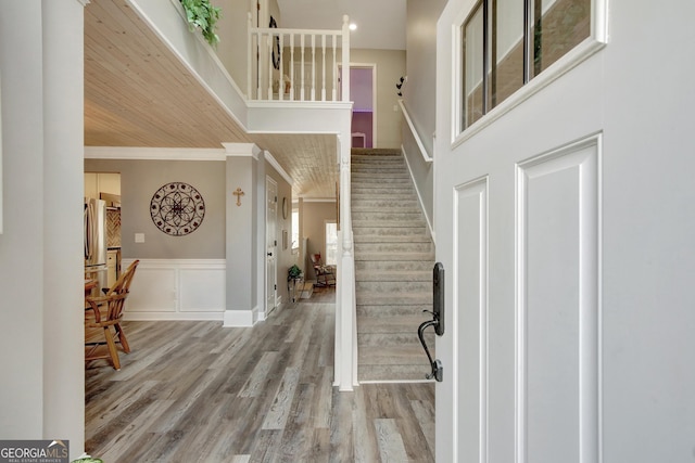 entrance foyer featuring crown molding, light wood-type flooring, and a high ceiling