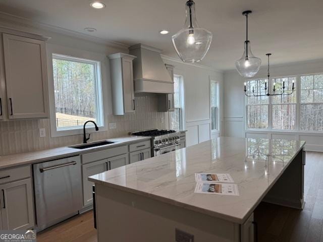 kitchen featuring a center island, a sink, appliances with stainless steel finishes, custom range hood, and ornamental molding