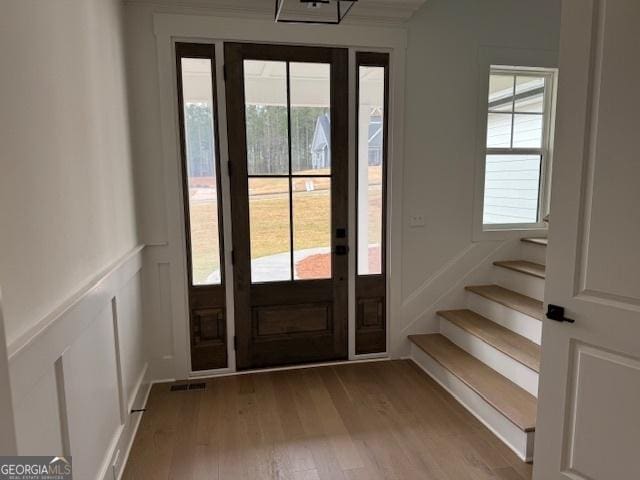 doorway featuring a wealth of natural light, a decorative wall, wood finished floors, and visible vents