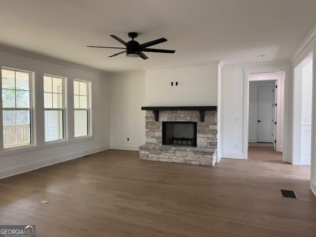 unfurnished living room with ceiling fan, baseboards, ornamental molding, and wood finished floors