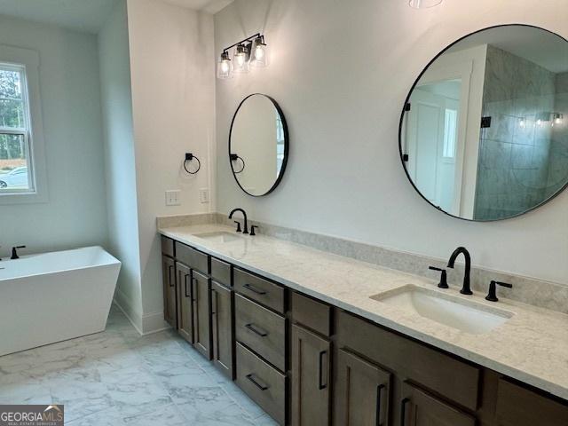 bathroom featuring double vanity, marble finish floor, a stall shower, and a sink