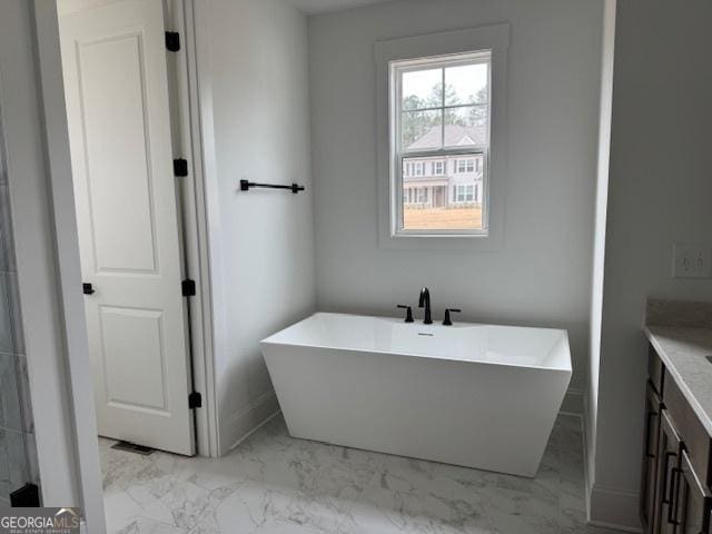 bathroom featuring vanity, marble finish floor, and a freestanding tub