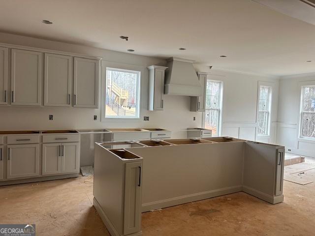 kitchen featuring gray cabinets, custom range hood, and a healthy amount of sunlight