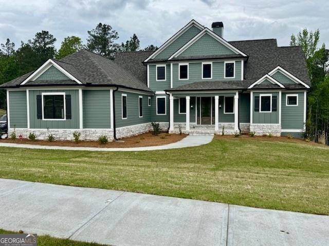 craftsman house with a chimney, a front lawn, roof with shingles, and covered porch