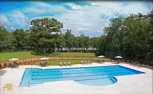 pool featuring a yard, a patio, and fence